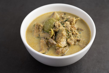 Chicken green curry in a white cup on the cement ground