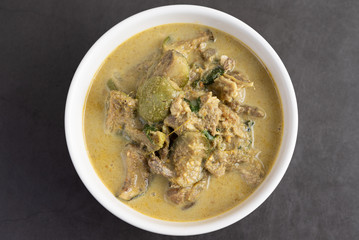 Chicken green curry in a white cup on the cement ground