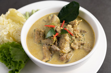 Chicken green curry in a white cup on the cement ground