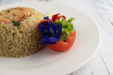 Shrimp fried rice on a white plate consisting of tomatoes and cucumbers.