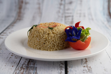 Shrimp fried rice on a white plate consisting of tomatoes and cucumbers.