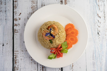 Shrimp fried rice on a white plate consisting of tomatoes and carrots.