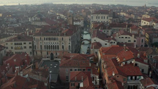 Aerial, tracking, drone shot over buildings and channels, on a evening, in Venice, Italy