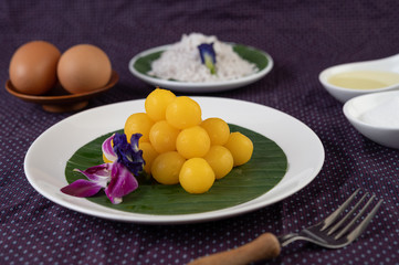 Thong Yod dessert on a banana leaf in a white plate with orchids and a fork