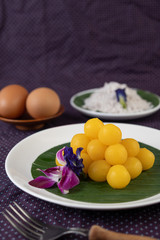 Thong Yod dessert on a banana leaf in a white plate with orchids and a fork