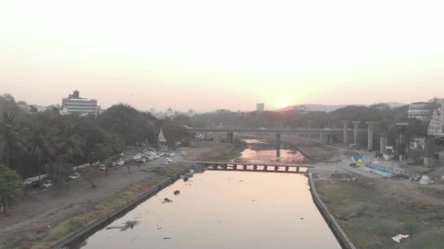 Slider drone shot over a river through a city at sunset