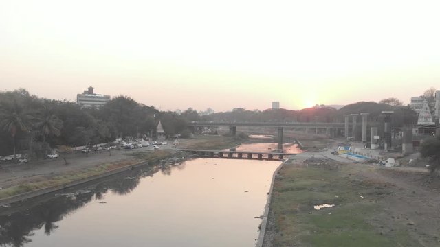 Rising drone shot over a river going through a city at sunset