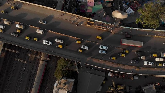 Overhead shot of a busy road bridge and train tracks underneath Mumbai