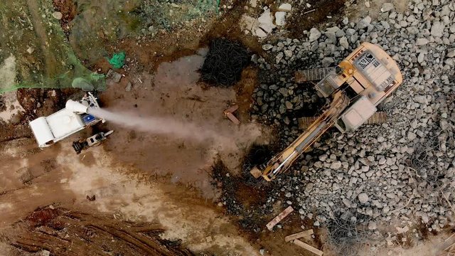 Aerial overhead moving upward view of a demolition site with excavator