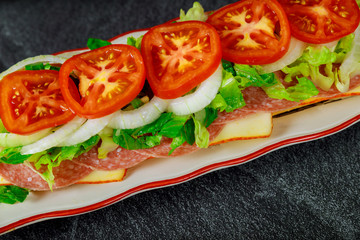 Long sandwich with muenster cheese, salami and vegetable.