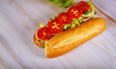 Sandwich with french bread, muenster cheese, salami and vegetable.