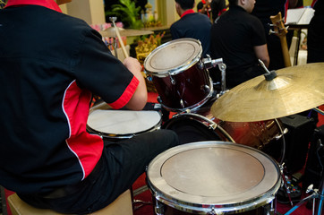 Unidentified Asian boy play drum set in music room
