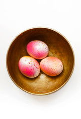 Hand painted easter eggs in golden metal bowl pink orange shiny colored paint pattern
