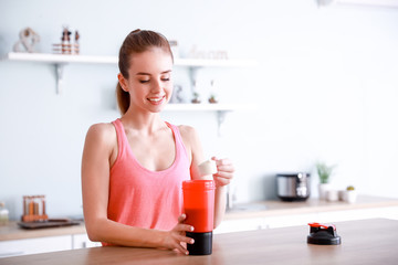 Sporty young woman making protein shake at home - obrazy, fototapety, plakaty