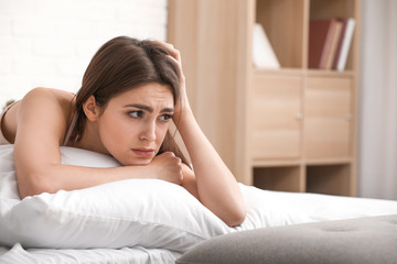 Depressed young woman in bedroom