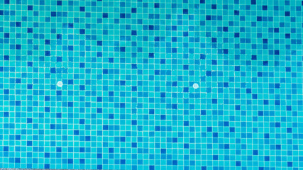 Swimming pool bottom is source tiles and water waves background. Summer texture of water surface overhead view.