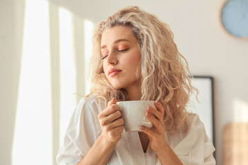 Morning of beautiful young woman drinking coffee in bedroom