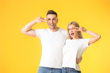 Fototapeta premium Happy young couple showing victory gesture on color background