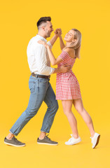 Happy dancing young couple on color background