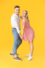 Happy dancing young couple on color background