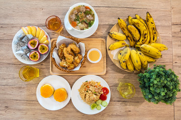 Breakfast served with milk, orange juice, croissants, fried rice with fruit and bread on wooden table. Balanced diet.