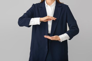 Businesswoman holding something on grey background, closeup