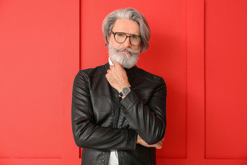 Stylish elderly man on color background