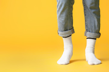 Male legs in socks and jeans on color background