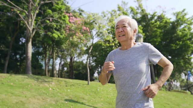 happy asian old man jogging running outdoors in a park