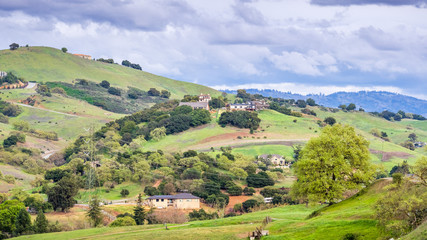 Fototapeta na wymiar Spring landscape on the hills of south San Francisco bay area; scattered houses built on the slopes; San Jose, Santa Clara county, California