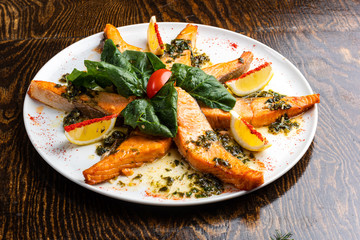 baked salmon on a white plate with slices with salad and spices