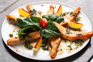baked salmon on a white plate with slices with salad and spices