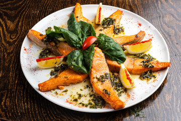 baked salmon on a white plate with slices with salad and spices