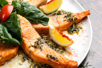 baked salmon on a white plate with slices with salad and spices