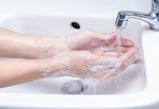 Woman washing hand with soap foam and tap water in bathroom. Hand clean under faucet on sink for personal hygiene to prevent flu and coronavirus. Good procedure of hand wash to kill bacteria, virus.