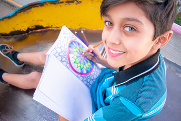 Photogenic child drawing a multicolored mandala