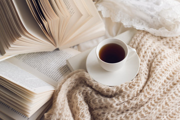 Many books  on the bed and a cup of coffee.