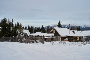     Snow- covered lake at dawn with boats on the shore.  Winter forest with snow-covered fir trees high in the mountains. Sunny February day in the spruce forest.      
