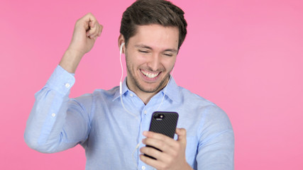 Dancing Young Man Listening Music on Smartphone on Pink Background