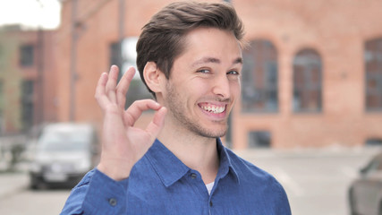 Okay Sign by Satisfied Young Man Standing Outdoor