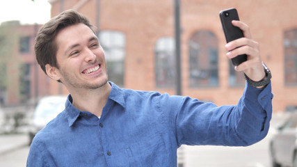 Outdoor Portrait of Young Man Taking Selfie on Phone