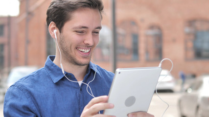Happy Young Man Listening Music on Tablet