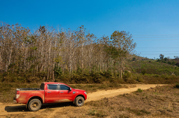 Red 4x4 truck, dirty with dust, on dirt road in the middle of nowhere in rural outback area. © Kamonchanok