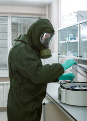 Man in a biohazard protective suit puts test tube with blood in a centrifuge. Testing for SARS-CoV-2, Covid-19, 2019-nCoV, SARS-CoV, MERS-CoV, Ebola