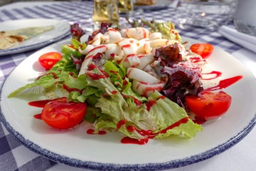 Tasty salad with different tomatoes, red pepper, lambs lettuce, cucumber, lettuce and lambs lettuce. Summer salad. Healthy snack. Concept for a tasty and healthy meal. White wooden background Close up