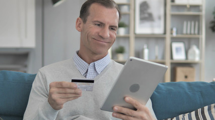 Online Shopping on Tablet by Middle Aged Man Sitting on Couch