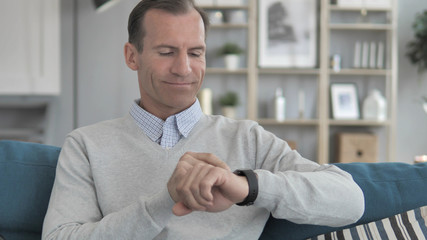 Middle Aged Man Relaxing on Couch and Using Smartwatch Applications