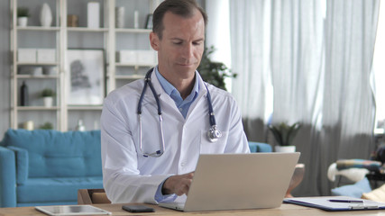 Senior Doctor Typing On Laptop in Clinic, Sending Email
