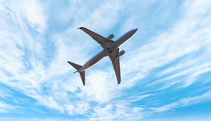 Commerical airplane flying under the clouds at sunset