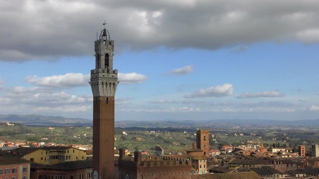 The view from the height of the tower Torre del Mangia (literally - the Tower of the Devourer) against the background of a cloudy sky. Italy. Warm sunny winter day.